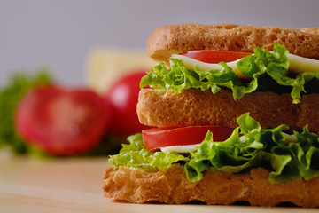 Homemade sandwich on a wooden board, close-up.
