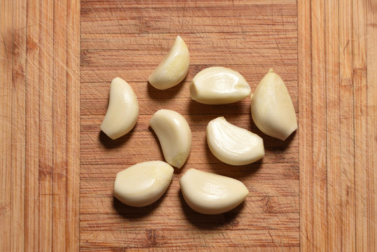 Fresh and peeled garlic is on the cutting board. close-up
