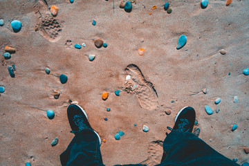mans sport shoes on a beach with little stones