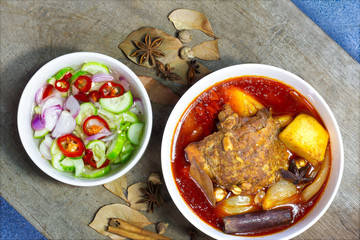 Masaman curry chicken in white bowl with cucumber and vegetables pickled sauce eat with curry Halal food.