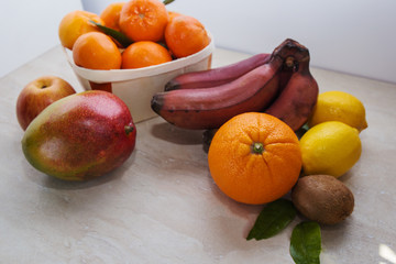 Fototapeta na wymiar Fresh healthy tropical fruits. Summer food, vitamins concept.Basket of ripe mandarins,apple,mango,red bananas,lemons,orange and kiwi.