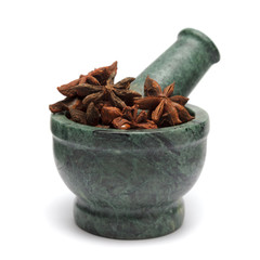 Organic Chinese Star Anise (Illicium verum) on marble pestle and over white background.
