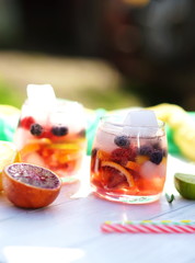 Summer cooling drink detox water from citrus lime, lemon, red orange, berries and ice cubes on outdoor