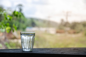 A glass of water on a wooden balcony.