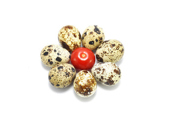 Quail eggs and red tomato on white closeup background
