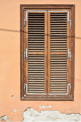 Fototapeta na wymiar Old brown wooden window with shutters and wall with cracked paint. Vintage background. Cyprus