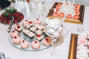 delicious sweets cupcakes with roses,pops and candy on table at wedding reception. candy bar. tasty pink sweets for celebrations events and showers. luxury stylish catering