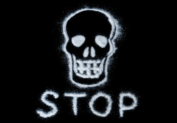 skull painted with white sugar and text stop on a black background. caution sign