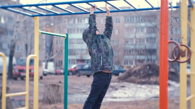 Boy crawling on the monkey bars in the yard of a city house. Games and walks on the Playground.
