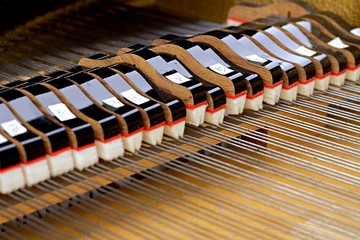 Inside a piano playing, dampers, felt hammers, action, metal strings and metal frame, red and white...