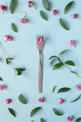 Creative layout. A fork on a blue background. Pattern of flowers and leaves. concept. Design. Flat lay