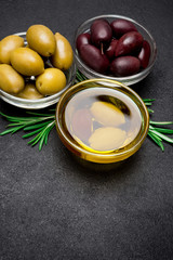 black and green olives isolated in glass bowl on dark concrete background