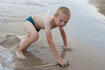 young boy playing in the sand and waves on the beach