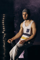 Muscular bodybuilder with dumbbells in smoke