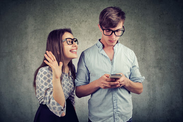 woman trying to bring attention of a handsome man ignoring her using a smartphone - obrazy, fototapety, plakaty