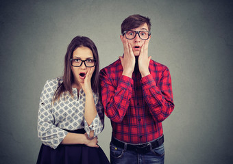 Scared nervous man and woman looking with widely opened mouth at camera