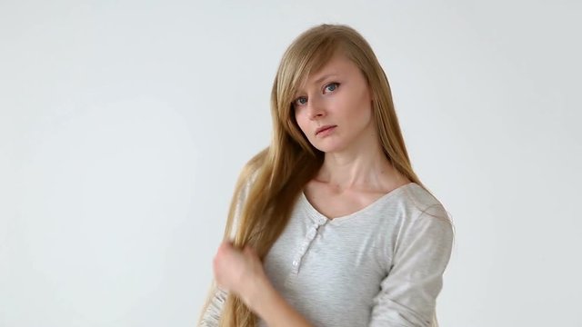 beautiful long-haired girl of European appearance with blond hair making different hairstyles over white background