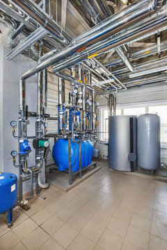 The interior of an industrial boiler house with a multitude of pipes, barrels and sensors
