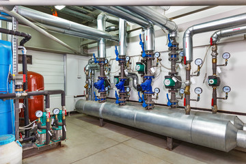 The interior of an industrial boiler house with a multitude of pipes, barrels and sensors