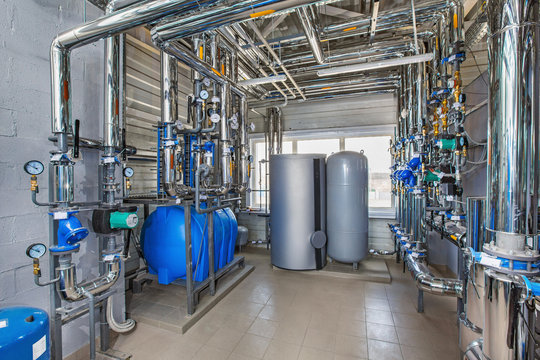 The interior of an industrial boiler house with a multitude of pipes, barrels and sensors