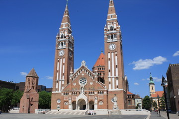 Fototapeta na wymiar The Votive Church and Cathedral of Our Lady of Hungary is a twin-spired roman catholic cathedral in Szeged, Hungary. It lies on Dom Ter square beside the Domotor tower.