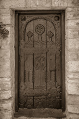 monochrome old carved door on a stone bulding and big hindges
