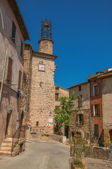 View of stone houses and tower in a street under blue sky, at the gorgeous medieval hamlet of Les Arcs-sur-Argens, near Draguignan. Located in the Provence region, Var department, southeastern France