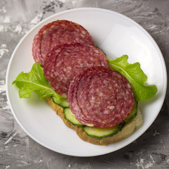 top view fresh sandwich with smoked sausage, cucumber slices and salad