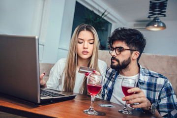 Young couple with laptop and credit card at home. Internet shopping concept