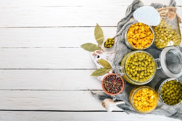 Marinated peas and corn in a jar. Stocks of food. Top view. On a wooden background. Copy space.