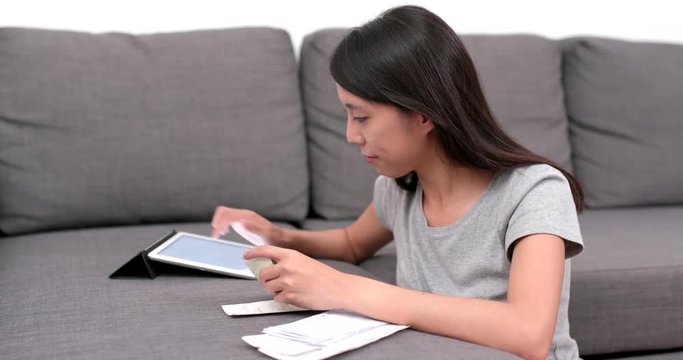 Woman record the daily expense of tablet computer at home