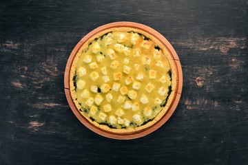 Casserole of spinach and cheese. On a wooden background. Top view. Copy space