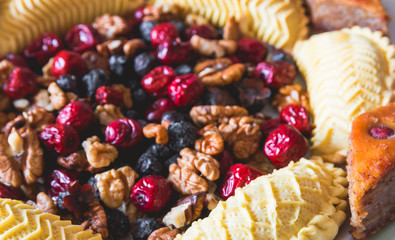 Sweets and desserts for the Novruz holiday on plate - shekerbura, baklava, walnuts and dried fruits