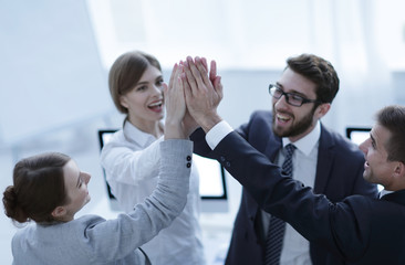 successful business team giving each other a high-five, standing in the office