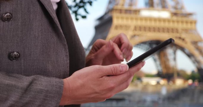 Close-up shot of white woman looking at photos on phone near Eiffel Tower