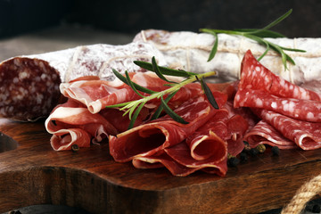 Food tray with delicious salami, prosciutto crudo,  fresh sausages and herbs. Meat platter with selection