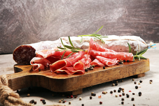 Food tray with delicious salami, prosciutto crudo,  fresh sausages and herbs. Meat platter with selection