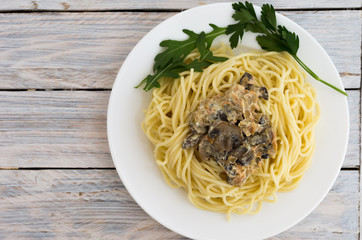 Boiled spaghetti and fried mushrooms on a white plate.