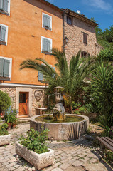 View of house facing a square with fountain in Chateaudouble, a quiet and tourist village with medieval origin on a sunny day. Located in the Var department, Provence region, southeastern France