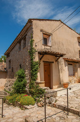 Fototapeta na wymiar Alley view with building and flowers in Chateaudouble, a quiet and tourist village with medieval origin on a sunny summer day. Located in the Var department, Provence region, southeastern France