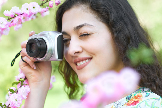 girl with camera taking pictures of pink flowers, face closeup