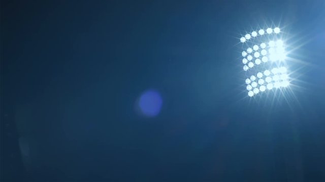 Background of football/soccer/sports stadium lights agains dark sky, net in front, 4k