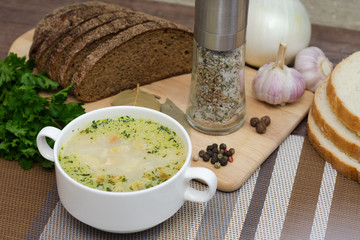 Mushroom soup with croutons in a white dish is on a wooden table.
