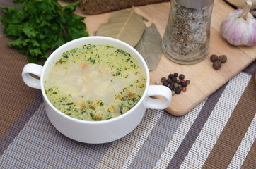 Mushroom soup with croutons in a white dish is on a wooden table.