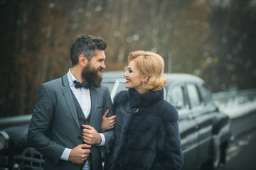 happy couple at black vintage retro car. Friends going on road trip travel on winter day