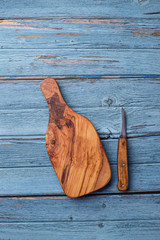 Cutting board and knife on blue wooden background