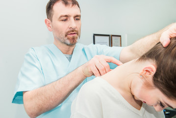 Obraz premium Male neurologist doctor examines cervical vertebrae of female patient spinal column in medical clinic. Neurological physical examination. Osteopathy, chiropractic, physiotherapy. Selective focus.