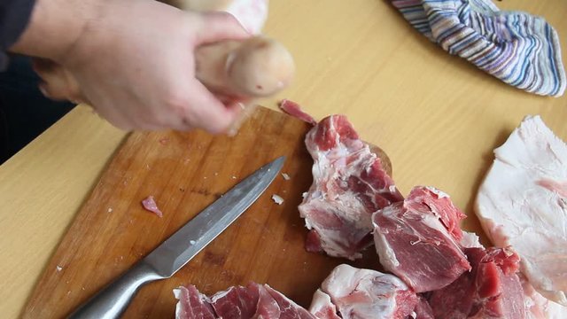 Man holding knife with hands, cutting, chopping, preparing pig raw, fresh meat steak for barbecue. Close up video footage of butcher cutting raw red bbq meat on cutting board.