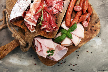 Food tray with delicious salami, ham,  fresh sausages and herbs. Meat platter with selection
