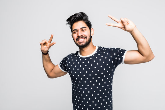 Portrait of happy young indian man showing victory on white background